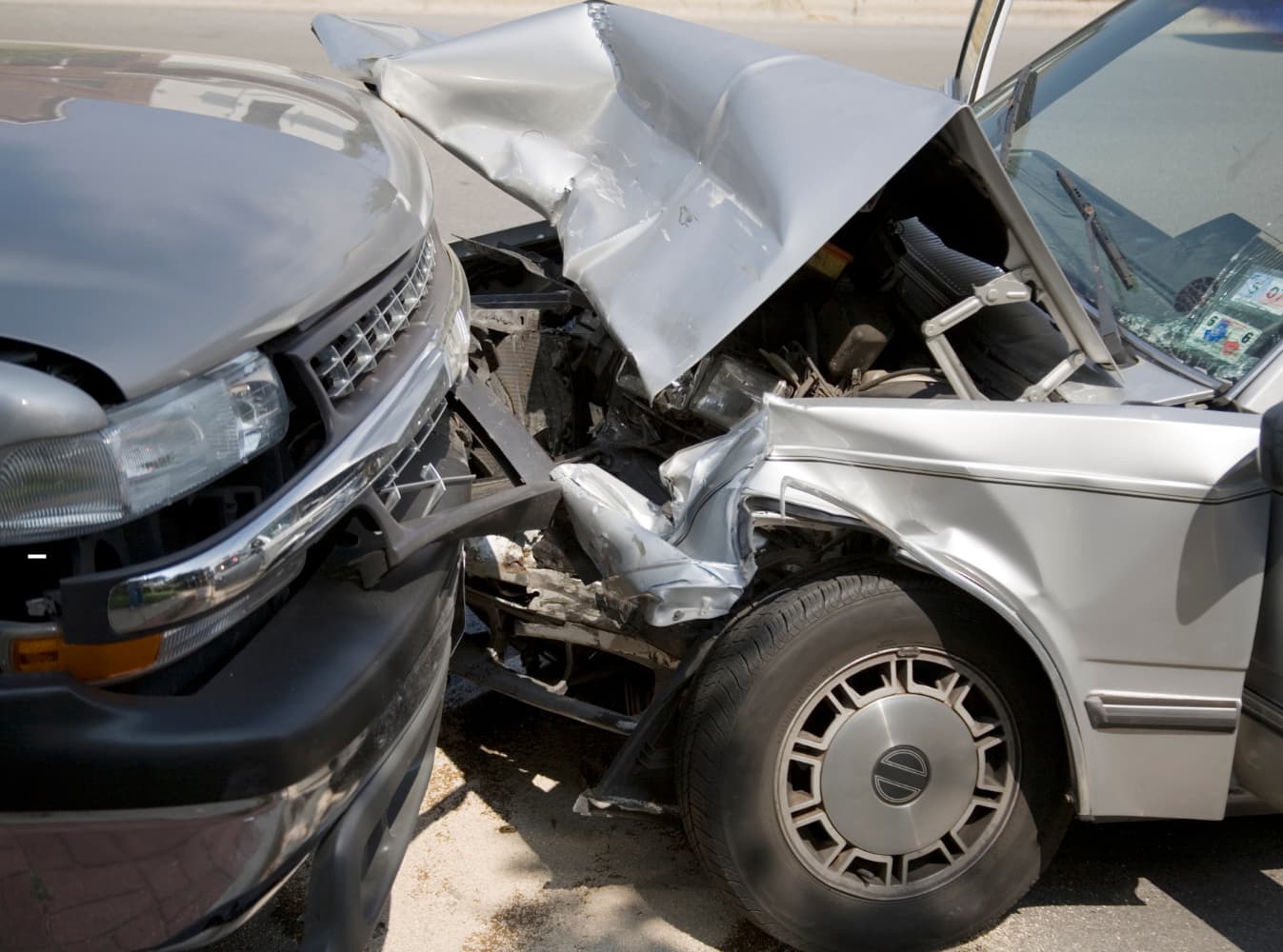 Two vehicles involved in a serious front-end collision, showing significant damage to both cars' front ends and crumpled hoods.
