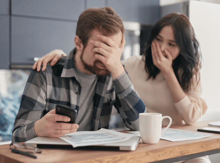 a couple stressed over bills holding a phone