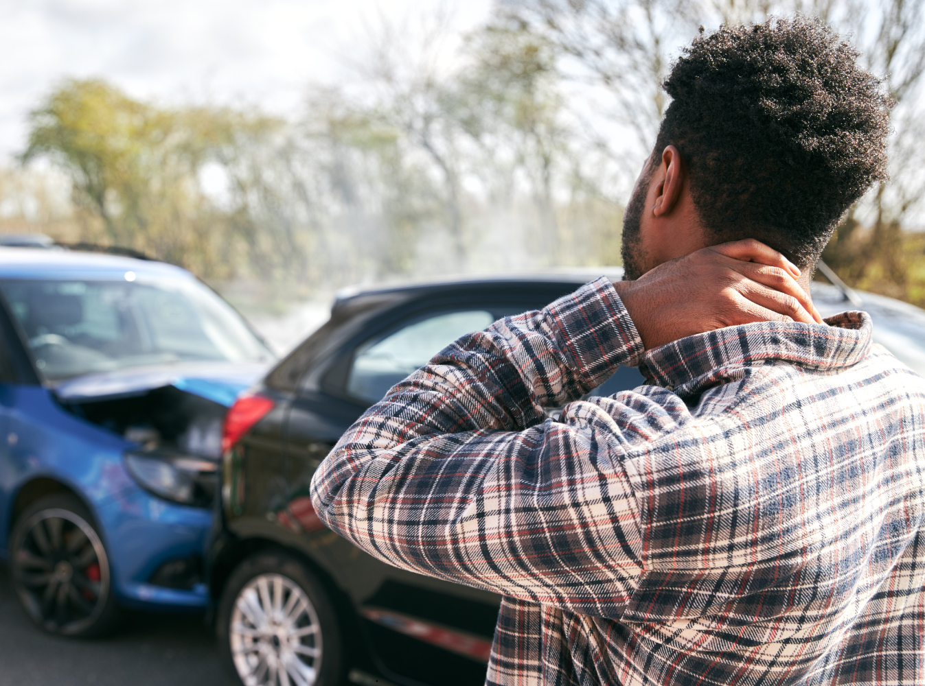 man standing in front of a rear end car accident holding his neck