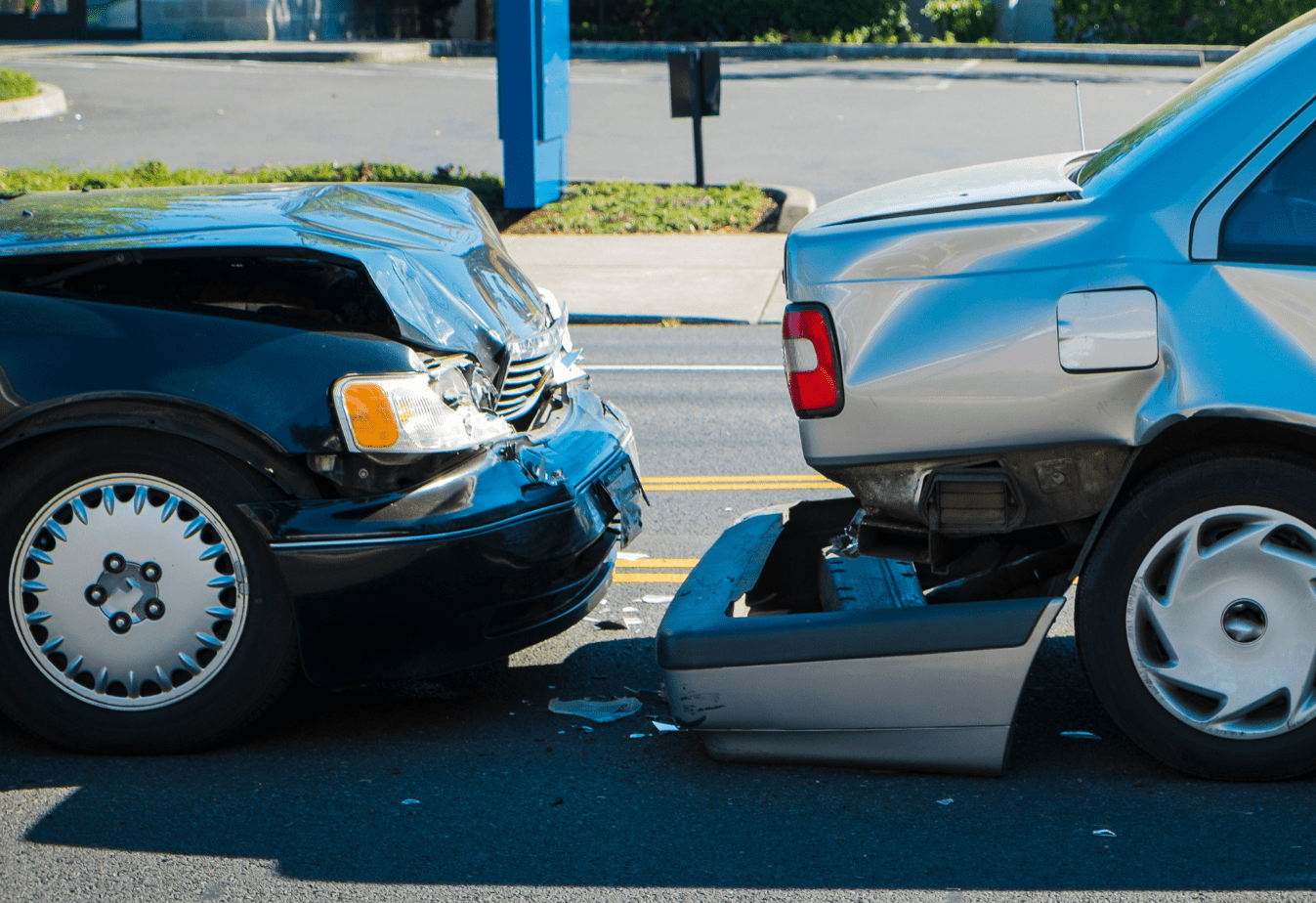 fender bender between a black car that hit a silver car and the silver car's bumper has fallen off