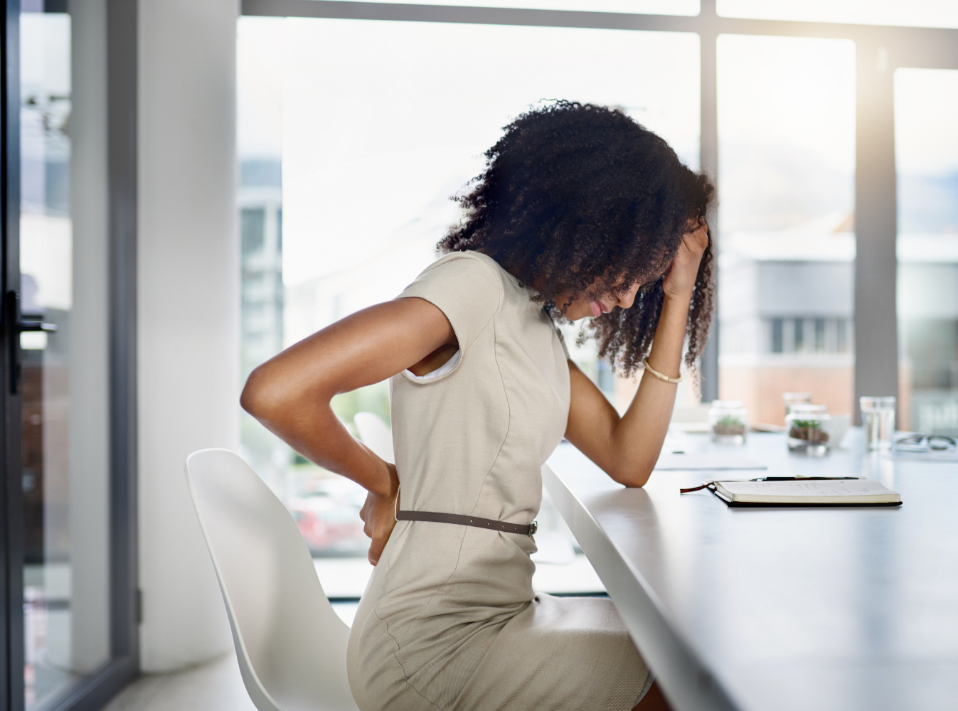 a woman sitting with back pain in a office