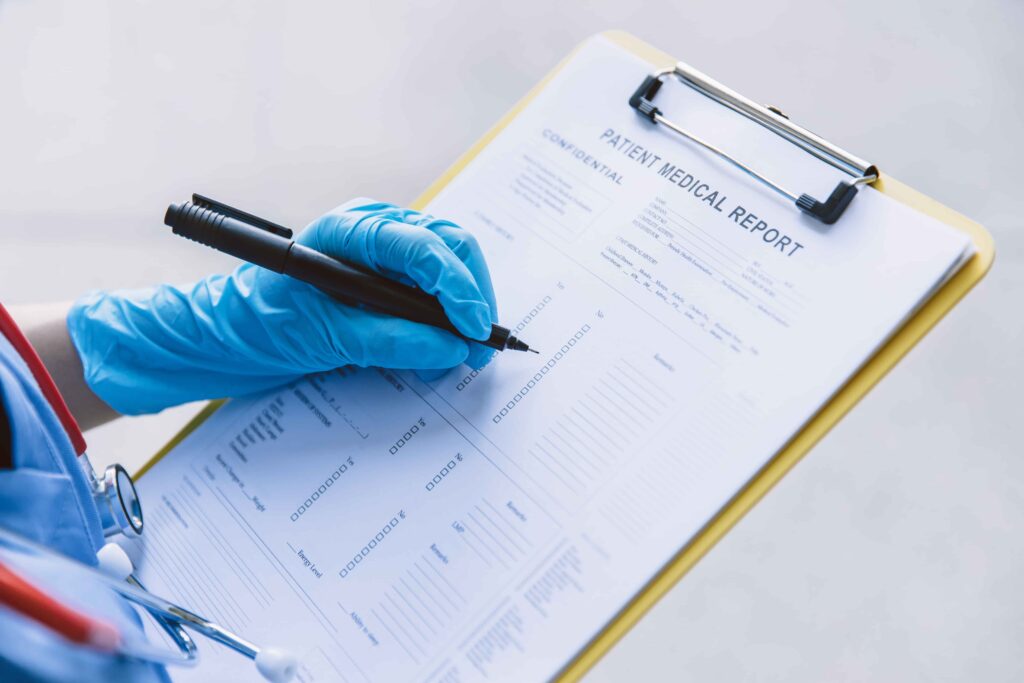 Doctor wearing medical gloves filling out a patient medical report on a clipboard.