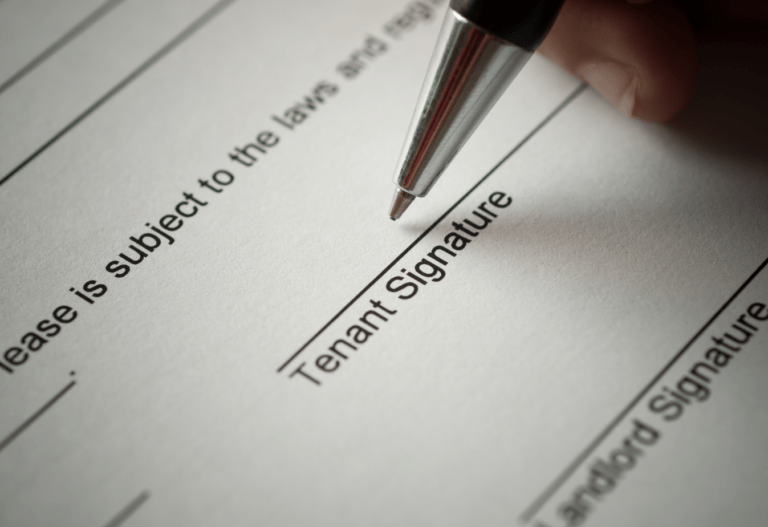 the point of a pen hovering over a document line that reads "tenant signature"