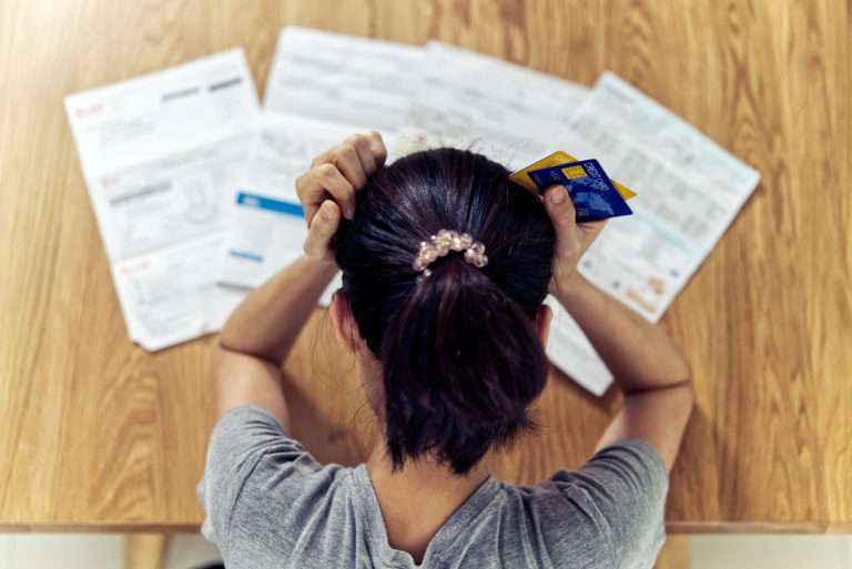 Top view of stressed young sitting woman hands holding the head worry about find money to pay credit card debt and all loan bills. Financial problem concept.