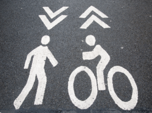 Car Accident Case signs pointing in opposite directions for pedestrians and bicycles painted on to pavement