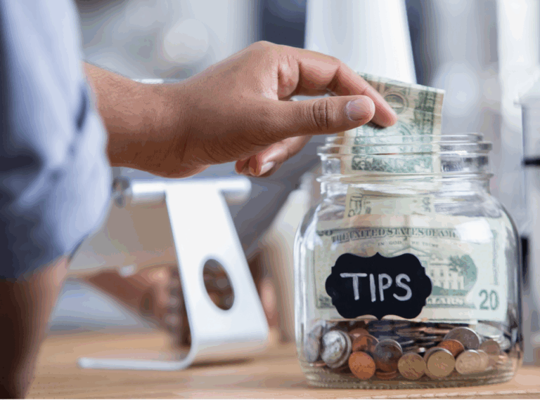 person putting cash into a tip jar in front of POS system