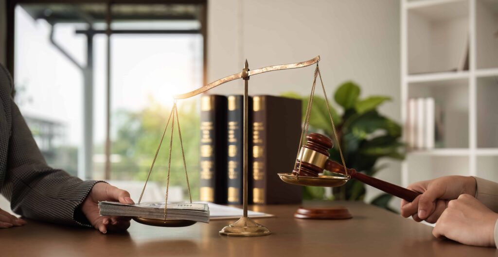 Scales of justice with money and a gavel on a lawyer’s desk representing legal compensation and settlement negotiations.