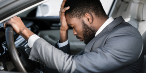 a man in the driver's seat holding his head