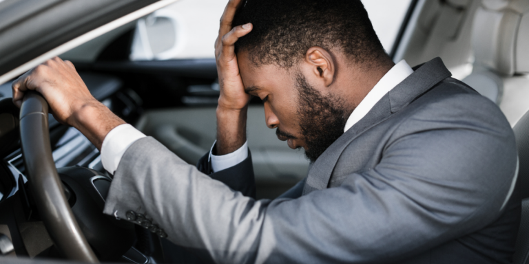 a man in the driver's seat holding his head